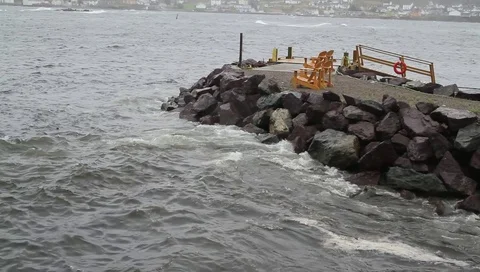 Waves hitting rocks surrounding a pier Video stock 89821336