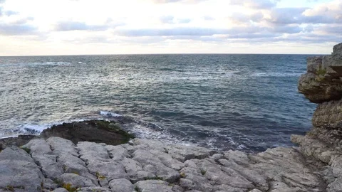 Waves hitting rocky cliff horizontal view Stock Footage 95977958