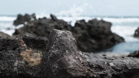 Waves hitting the shore rocks on the beach on a cloudy day Stock Footage 138695354
