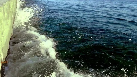 Waves hitting the stone pier on a sunny day Stock Footage 78973551