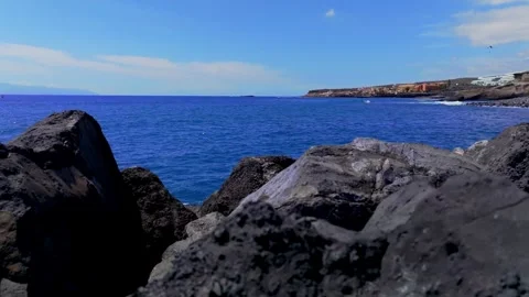 Waves Hitting Volcanic Coastal Rocks With Paragliding Seen on Sunny Tenerife Video stock 335942718