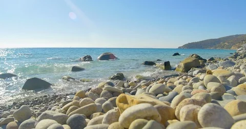 Waves landing on stone beach. Clear blue water. Stock Footage 82328972