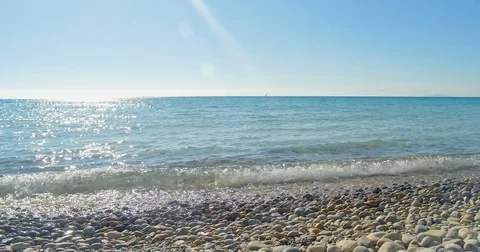 Waves landing on stone beach. Clear blue water. Stock Footage 82405768