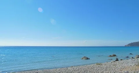 Waves landing on stone beach. Clear blue water. Stock Footage 82428926