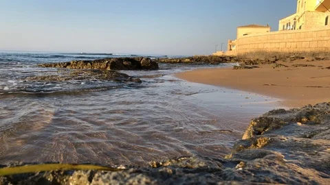Waves lap at coastline rocks with stone houses. Видео 118270687