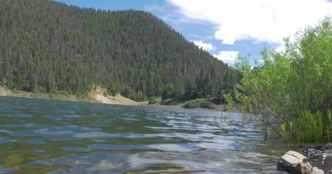 Waves Lap the Rocky Shoreline on a Secluded Mountain Lake - 4K Stock Footage 65526692