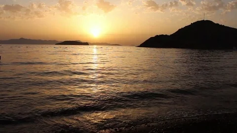 Waves lap shore in bay at sunset Stock Footage 85016545