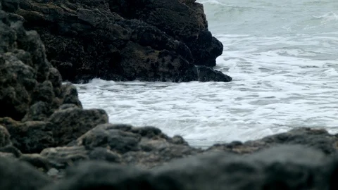 Waves lap volcanic rock on the beach Stock Footage 89702615