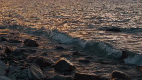 Waves lapping against rocky shore at sunset Stock Footage 140612000