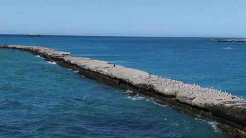 Waves lapping against a stone breakwater illuminated by sunset light, top view Stock Footage 232923261