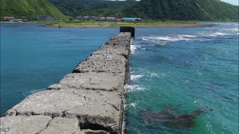 Waves lapping against a stone breakwater illuminated by sunset light, top view Stock Footage 232967426