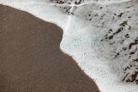 Waves lapping on the black sand Stock Photos