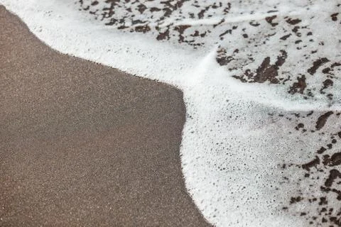 Waves lapping on the black sand Stock Photos