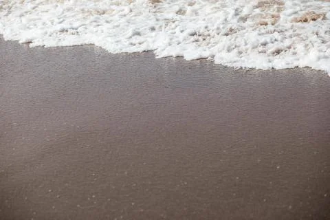 Waves lapping on the black sand Stock Photos