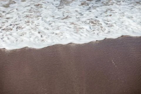 Waves lapping on the black sand Stock Photos