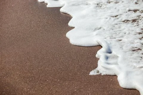 Waves lapping on the black sand Stock Photos