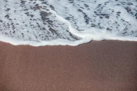 Waves lapping on the black sand Stock Photos