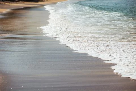 Waves lapping on the black sand Stock Photos