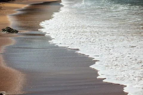 Waves lapping on the black sand Stock Photos