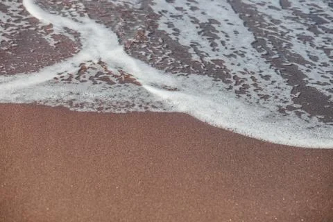 Waves lapping on the black sand Stock Photos