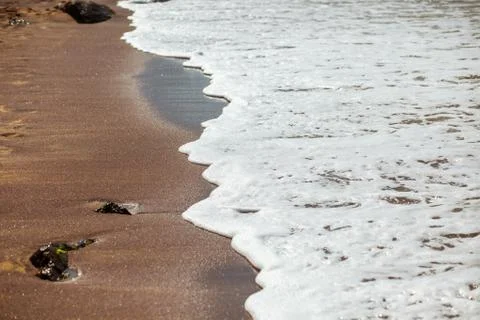 Waves lapping on the black sand Stock Photos