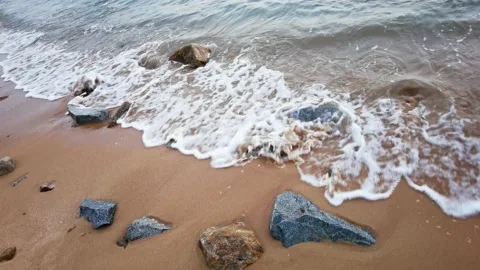 Waves lapping at colorful rocks, white waves on yellow sand, 4k 스톡 동영상 159577555