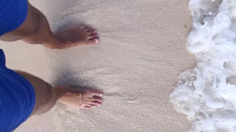 Waves lapping over mans feet Stock Footage