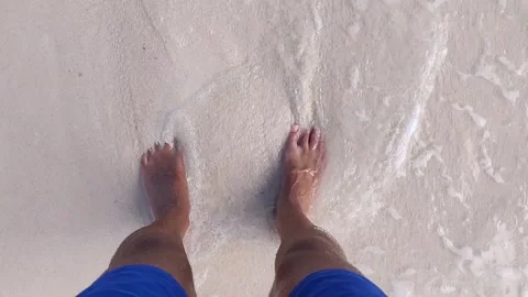 Waves lapping over mans feet Stock Footage 146387971