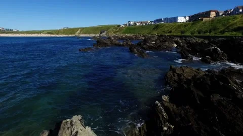 Waves lapping on rock in foreground with view of Fistral bay and distant beach Stock Footage 66447879