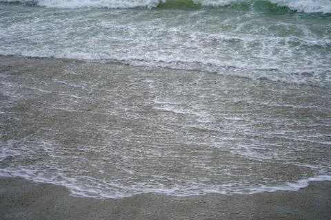 Waves lapping on a sandy beach shore 写真素材
