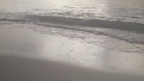 Waves lapping on a sandy seashore at sunrise Vidéo 75693720