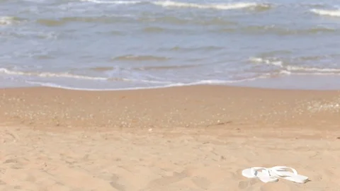 Waves lapping on a sandy shore, no people, beach Slippers on the beach Stock Footage 97259478
