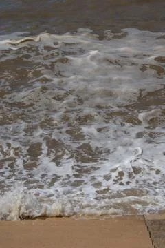Waves lapping at seaside steps Foto stock