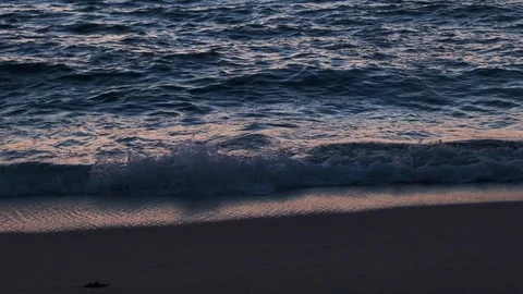 Waves lapping on shore on a beach at dusk in slow motion. Close up. Stock Footage 115758948