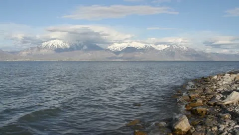 Waves lapping on shore of lake with mountians in background Stock Footage 10909091
