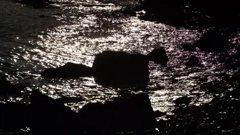 Waves lapping onto silhouette of rocks Stock Footage 233902960