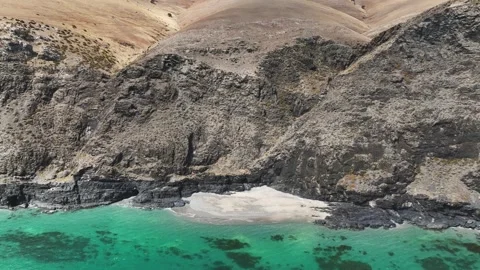 Waves lapping on a small beach below towering cliffs Stock Footage 321790554
