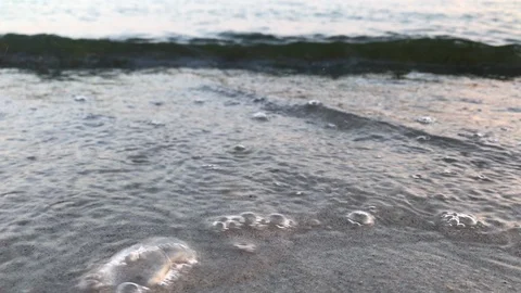 Waves making bubbles on the beach during sunset Stock Footage 93357802
