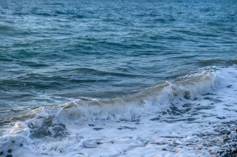 Waves of the Mediterranean sea in the rays of sunset Stock Photos