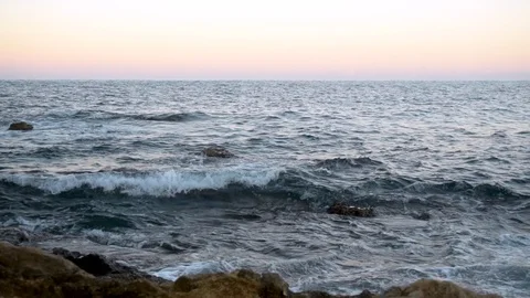 Waves on the Mediterranean Sea. Waves hit the rocks at pink sunset. Slow motion Stock Footage 120081972