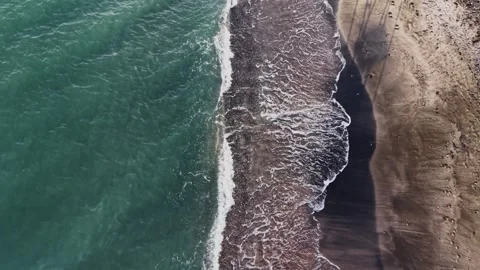 Waves meet shore at a beach with clear water and sandy land Vidéo 335141601