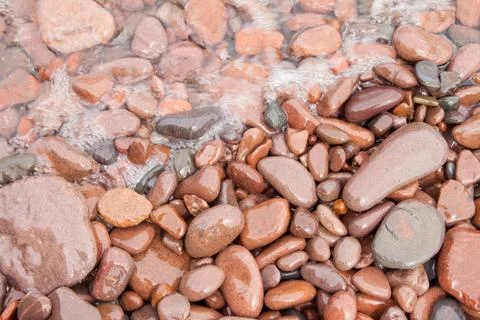 Waves in motion on rounded shore rocks Stock Photos