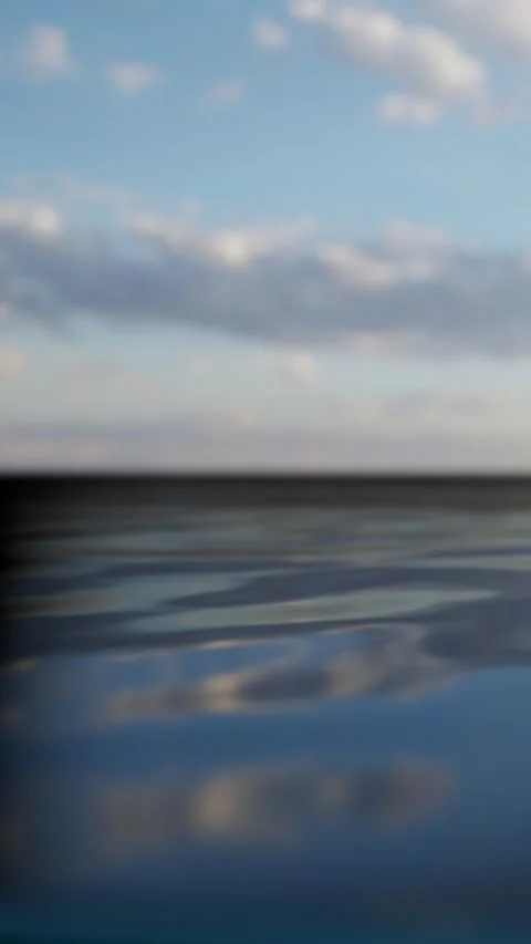 Waves move gently across the water under a cloudy sky in the afternoon Stock Footage 339396533