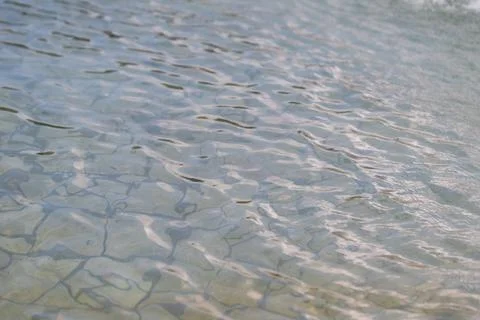 Waves move gently on a clear water surface reflecting light on a sunny day .. Stock Photos