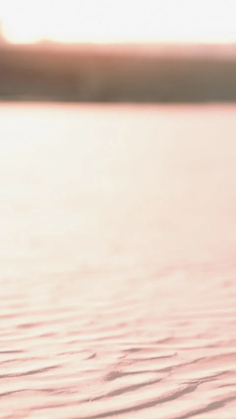 Waves move gently on the surface of water at sunset near a sandy shore Stock Footage 337941500