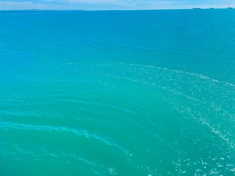Waves move softly on the surface of the blue water under a bright sky. Ships  Stock Photos