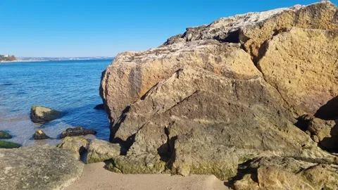 Waves moving around large coastal rock formations under bright blue sky Stock Footage 322161147