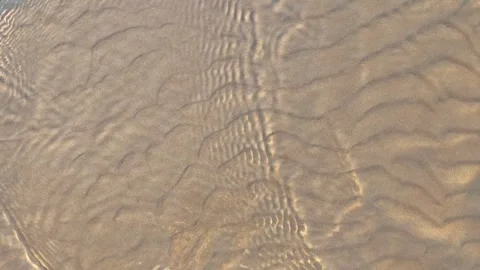Waves moving on sand create patterns at the beach during sunset Stock Footage 340462131