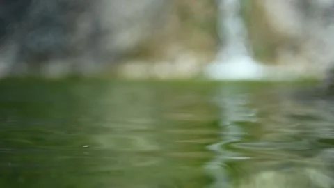 Waves in a natural pool with green water and a waterfall (slow motion, bokeh) Video stock 211763517