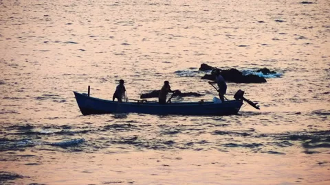 Waves of the ocean colors from the sunset, far away is small fishing boat sails Stock Footage 108136389